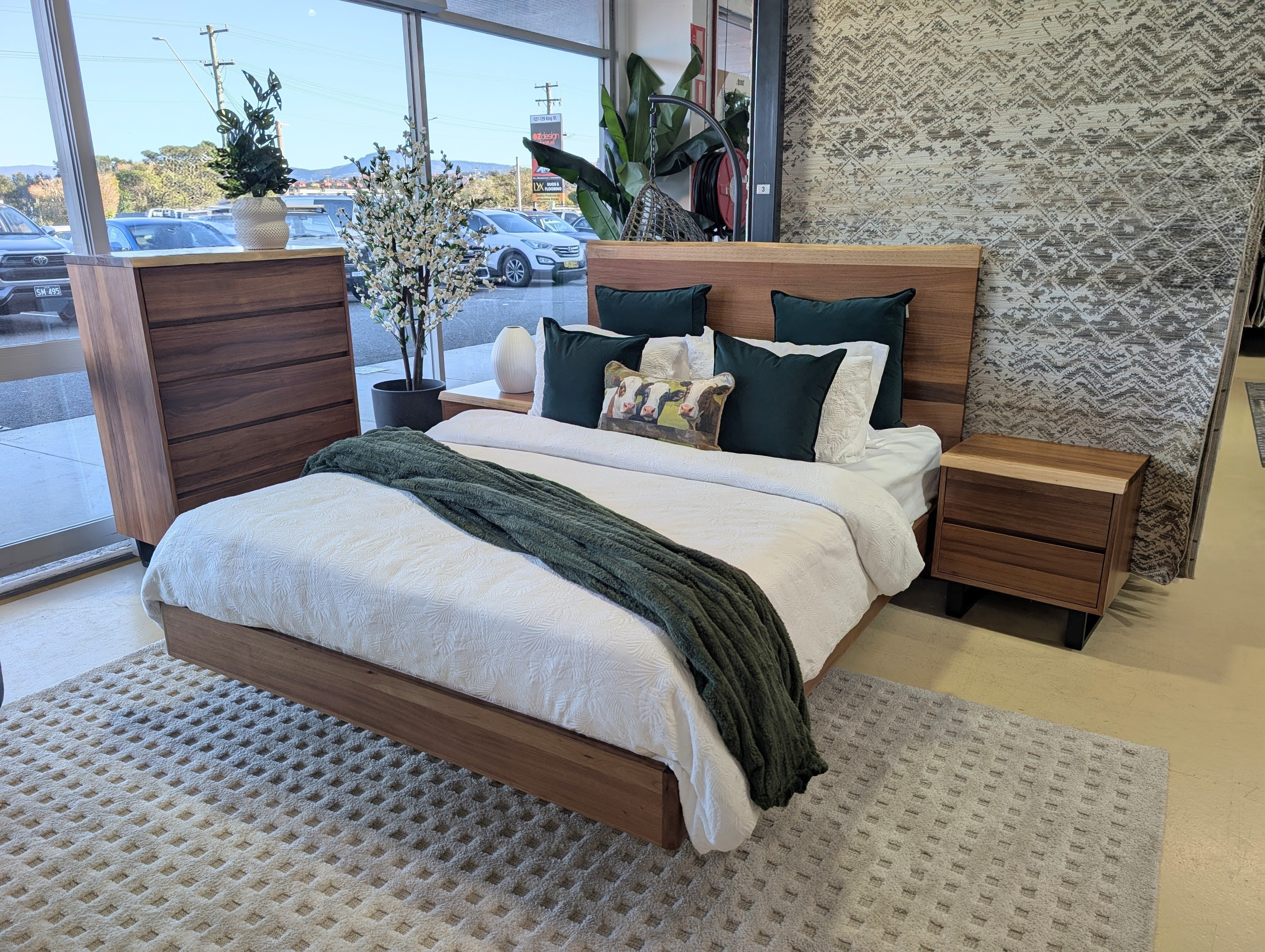 Wooden bed with bedding and pillows in a showroom setting